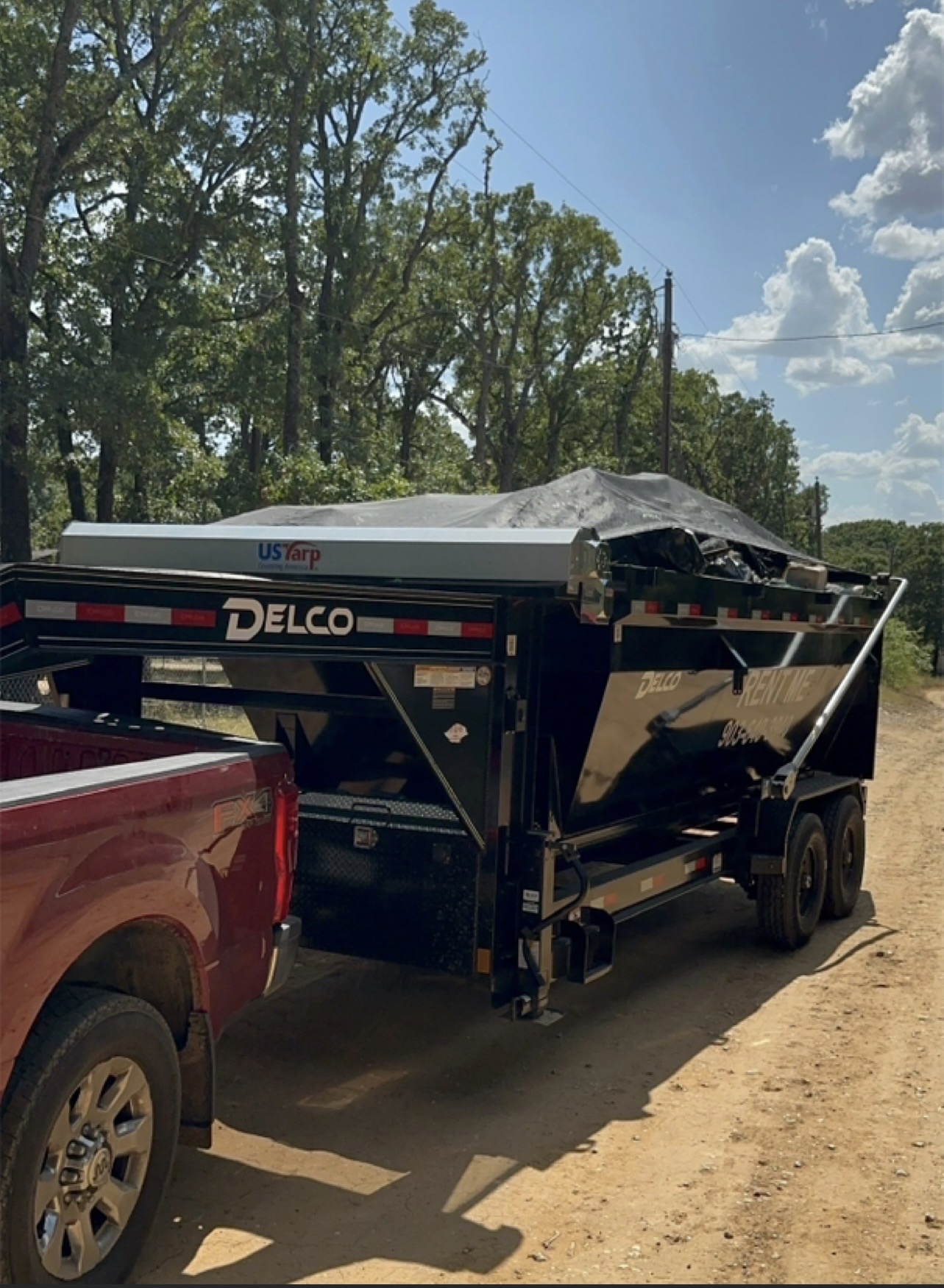 HomeHaven truck hauling a loaded, tarped 16-yard dumpster out of a North Texas job site